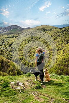 Young sports woman hiking in a magnificent landscape of the summit in the Basque country with her Border Collie