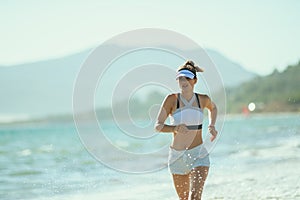 Young sports woman on seacoast in evening jogging