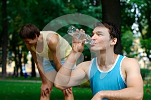 Young sportsman drinking water at the park