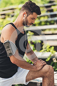 young sportsman in earphones with smartphone in running armband case doing
