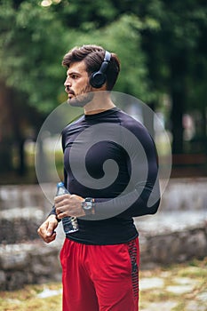 Sportsman listening to music while doing exercising in the park. Fitness, sport, lifestyle concep