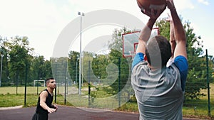 Young sportsman playing basketball on the court outdoors with friends, dribbling and missing the basket