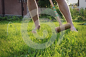 Young sportsman plays cricket, english traditional game, on the garden. Boy is trying to hit ball to the last goal before target.