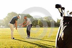 Young sportsman practicing golf with his teacher photo