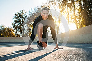 Young sportsman preparing for run, sunset light