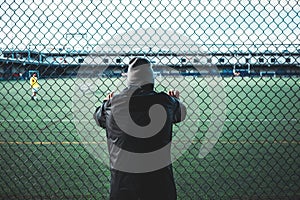 Young sportsman resting after sport excersion run near the fence. Concept