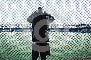 Young sportsman resting after sport excursion run near the fence. Concept