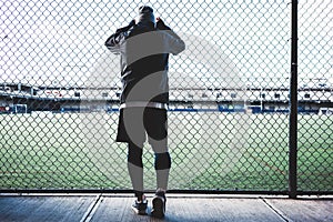 Young sportsman resting after strong and fast run near the fence. Concept