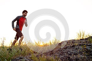 Young Sportsman Running on the Rocky Mountain Trail at Sunset. Active Lifestyle