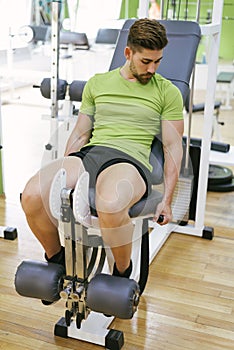 Young sportsman almost shouting when doing leg extension with heavy weight