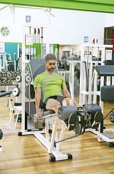 Young sportsman almost shouting when doing leg extension with heavy weight