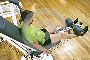 Young sportsman almost shouting when doing leg extension with heavy weight