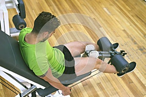 Young sportsman almost shouting when doing leg extension with heavy weight