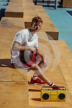 young sportsman sitting with ball near