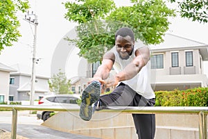 Young sportsman stretching leg after outdoor running in the park. African man preparing, practicing, training. sport, lifestyle,