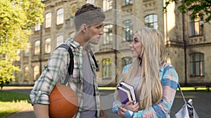 Young sportsman talking with beautiful blonde near college, asking for date