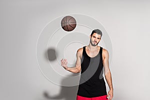 young sportsman throwing basketball ball and looking at camera