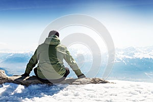 Young sportsman or traveler sitting on stone and looking on horizon. Mountain range on background. Beautiful Landscape.