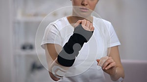 Young sportswoman applying titan wrist brace rehabilitation after trauma, health