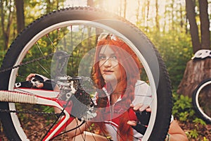 Young sportswoman bicyclist repairing her mtb bike in the forest