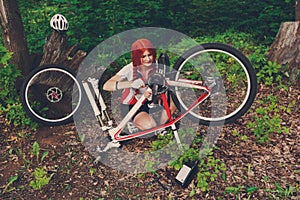 Young sportswoman bicyclist repairing her mtb bike in the forest