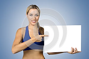 Young sportswoman holding blank board and pointing on it