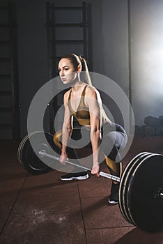 Young sportswoman preparing to raise barbell