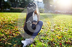 Young sportswoman stretching and preparing to run. Fitness sport woman in fashion sportswear doing exercise in the city park. Outd