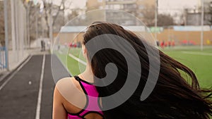 Young sporty asian girl walks at stadium after training and lets her hair down.