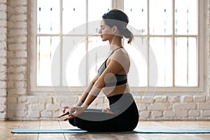 Young sporty attractive woman practicing yoga in Half Lotus pose