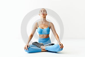 Young sporty attractive woman in sportswear practicing yoga, meditating in Lotus pose Padmasana