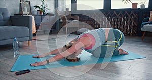 Young sporty beautiful Caucasian woman doing yoga stretching workout at home to keep healthy and fit on quarantine.