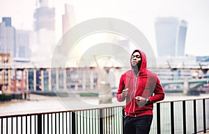 Young sporty black man runner running on the bridge outside in a city.