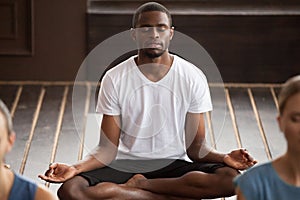 Young sporty black man sitting in Sukhasana exercise