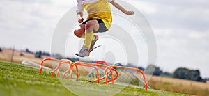 Young Sporty Boy Jumping Over Hurdles. Outdoor Soccer Agility Training on Summer Day