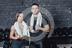 Young sporty couple guy and girl standing in gym. During this, the white scumbag is held on the neck.