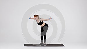Young Sporty Female Doing Dumbbell Bent Over Fly Exercise In Studio