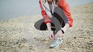 Young sporty female tying shoe lace and preparing to run