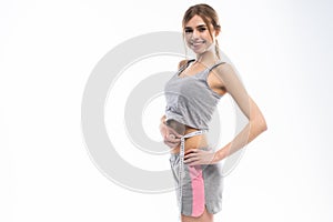 Young, sporty, fit and beautiful girl with the measuring tape over white background