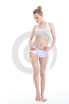 Young, sporty, fit and beautiful girl with the measuring tape over white background.