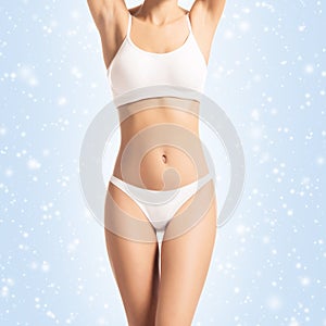 Young, sporty, fit and healthy girl over winter background. Sporty female body in white slimming underwear. Christmas