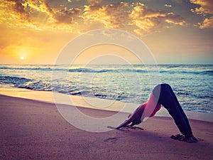 Young sporty fit woman doing yoga at beach on sunset