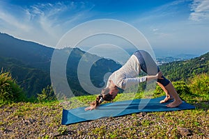 Young sporty fit woman doing yoga oudoors in mountains