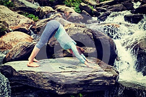 Young sporty fit woman doing yoga oudoors at tropical waterfall