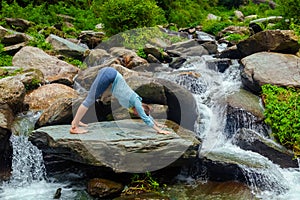 Young sporty fit woman doing yoga oudoors at tropical waterfall