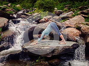 Young sporty fit woman doing yoga oudoors at tropical waterfall