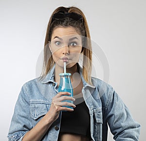 Young sporty girl in casual dess with energy drink making face