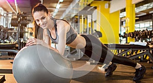 Young sporty girl doing plank exercise on a fitness ball at gym. Panoramic view