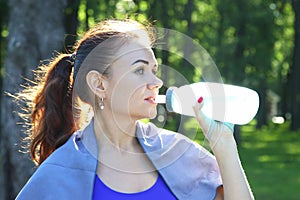 Young sporty girl drinking water from a bottle