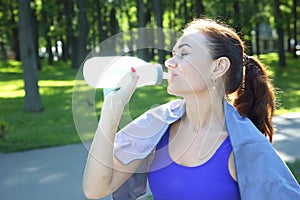Young sporty girl drinking water from a bottle